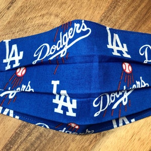 May include: A blue face mask with a white LA Dodgers logo and baseball pattern.