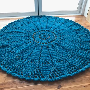 May include: A teal blue crocheted round rug with a circular pattern in the center.