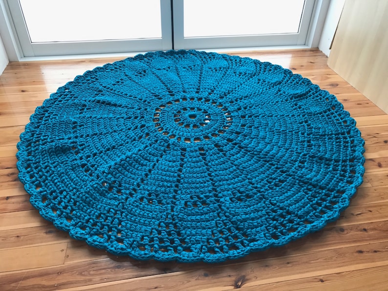 May include: A teal blue crocheted round rug with a circular pattern in the center.