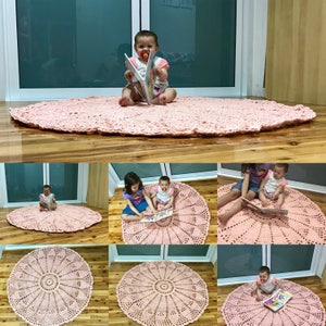 May include: A pink crocheted round rug with a circular pattern in the center. The rug is shown in different rooms with children sitting on it and reading books.