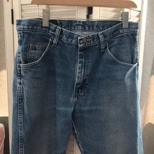 May include: A pair of blue denim jeans with a classic five-pocket style. The jeans have a straight leg and a button fly.