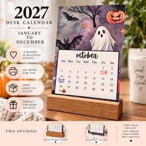 May include: A 2027 desk calendar featuring a Halloween-themed illustration for October with a ghost, bats, and a jack-o'-lantern. The calendar is displayed in a rectangular wooden stand, showing the month of October with dates and holiday icons.