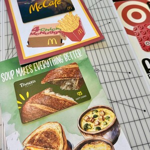 Puede incluir: Dos tarjetas de regalo, una para McCafe de McDonald's y otra para Panera Bread. La tarjeta de McDonald's tiene una imagen de papas fritas y nuggets de pollo. La tarjeta de Panera Bread tiene una imagen de una hogaza de pan y un taz&oacute;n de sopa. El texto en la tarjeta de Panera Bread dice "La sopa lo hace todo mejor" y "Tarjeta de regalo de 25 &euro;".