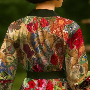 Puede incluir: Una bata de seda colorida con una faja negra. La bata presenta un estampado floral y animal vibrante con tigres, pavos reales y mariposas.