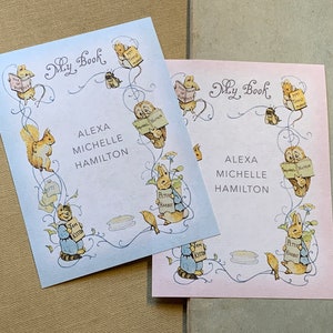 May include: Two personalized bookplates with a blue and pink background. The bookplates feature a whimsical design with a variety of animals and the text "My Book". The name "Alexa Michelle Hamilton" is printed on both bookplates.
