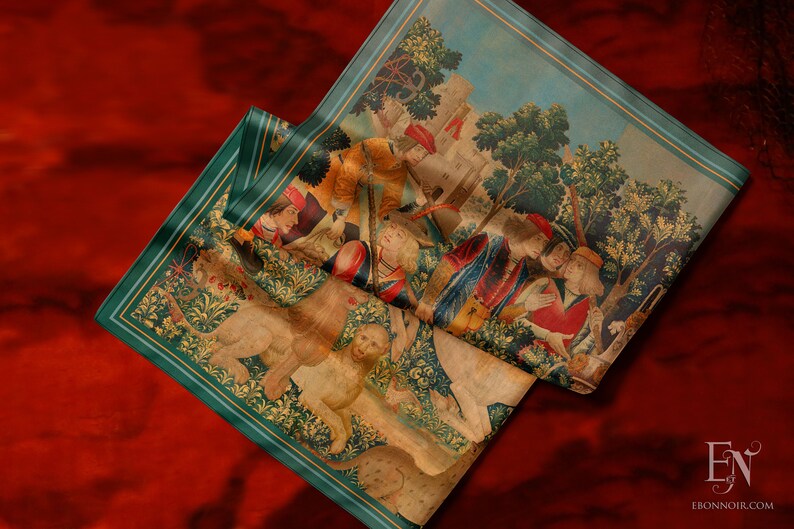May include: A tapestry depicting a scene from the hunt of the unicorn. The tapestry features a lion, a unicorn, and several people in medieval clothing. The tapestry is folded in half and has a green border.