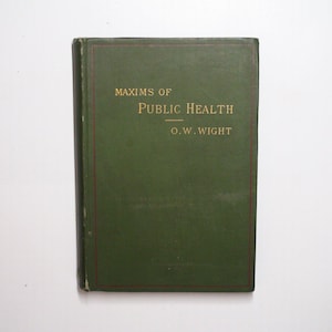 May include: A hardcover book with a dark green cover featuring gold embossed text that reads Maxims of Public Health by O.W. Wight. The front cover includes a thin red rectangular border line framing the title and author information.