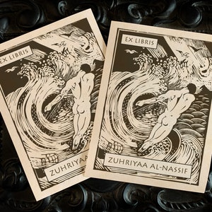 May include: Two brown paper bookplates with black ink illustrations of a nude figure swimming in a wave. The text "Ex Libris" is at the top of each bookplate. The bottom of the bookplates reads "Zuhriyaa" and "Zuhriyaa Al-Nassif".