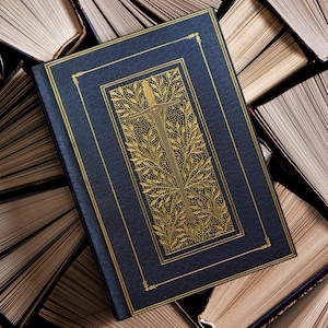 May include: A navy blue book with gold leaf detailing and a decorative gold design on the cover. The book is surrounded by other books with aged, yellowed pages, creating a vintage aesthetic.