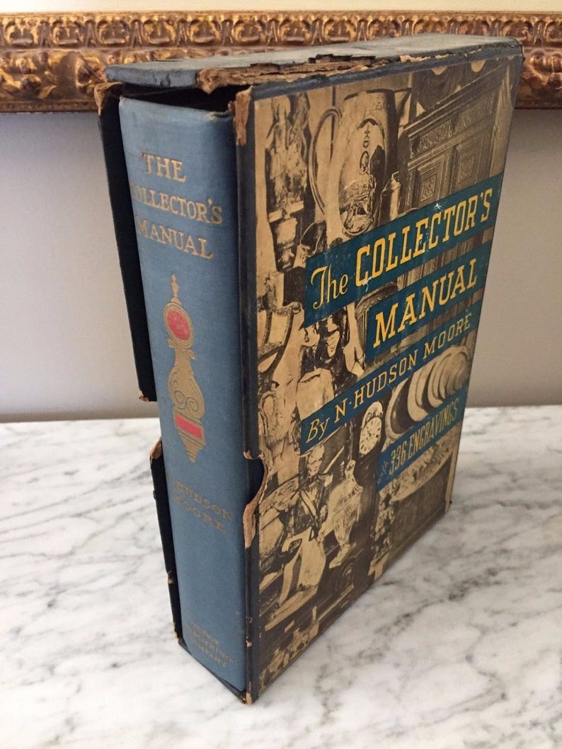 May include: An antique book titled "The Collector's Manual" by N. Hudson Moore. The book is in a blue cover with gold lettering and a decorative design. The book is housed in a worn, illustrated slipcase with the title and "336 Engravings".