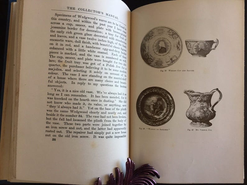 May include: An open book with illustrations of antique dishware, including a plate, cup, and pitcher. The text on the page describes Wedgwood's wares and their history. The book is open to a page with text and illustrations.