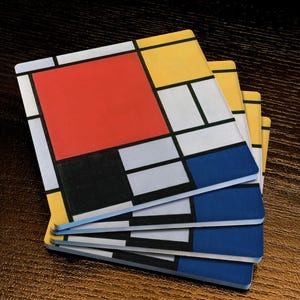 May include: A stack of square coasters with a Mondrian-style design. Each coaster features a grid of black lines and primary colors: red, yellow, and blue, along with white and gray. The coasters are stacked on a dark wooden surface.