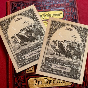 May include: Two vintage bookplates with an ornate border and a black and white illustration of a witch riding a black goat. The text "Ex Libris" and "Michaela Löfgren" are printed on the bookplates.