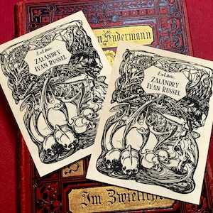 May include: Two vintage bookplates featuring black and white illustrations of a skull and bones design. The text on the bookplates reads "Ex Libris: ZALANDRY IVAN RUSSEL".