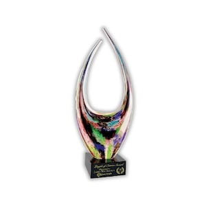 May include: A colorful art glass sculpture with a teardrop shape, featuring streaks of pink, green, blue, and black. The sculpture sits on a black base with engraved text. A decorative piece.