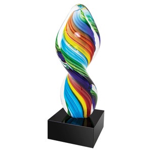 May include: A colorful glass sculpture with a swirling, abstract design. The sculpture features a rainbow of colors, including red, yellow, green, and blue, and is mounted on a black square base. The glass has a glossy finish.