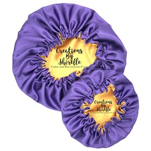 May include: Two purple satin hair bonnets with gold satin lining. The bonnets have the text "Creations By Shirrelle" and "Custom satin hair accessories & more" printed on them.