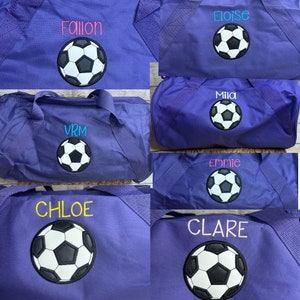 Purple duffel bag with two handles. The bag is embroidered with a name and appliquéd with a soccer ball centered on front of bag.