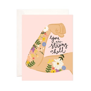 May include: A pink card with a floral illustration of a bicep flexing. The text reads "you are strong as hell."