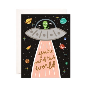 May include: Greeting card featuring a cartoon illustration of a green alien in a silver UFO. The UFO emits a pink beam with the gold text "you're out of this world" against a black space background with planets and stars.
