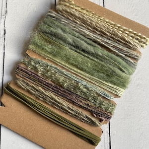 May include: A selection of green and brown yarn samples on cardboard. The yarns vary in texture and shade, including smooth, fuzzy, and braided styles. The color palette ranges from light olive to deep forest green, with hints of brown and beige.