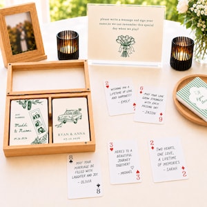 Op de afbeelding: Een houten doos met aangepaste speelkaarten met trouwthema-illustraties en tekst, naast verschillende losse kaarten met handgeschreven berichten. Een bordje leest, please write a message and sign your name, so we can remember this special day.