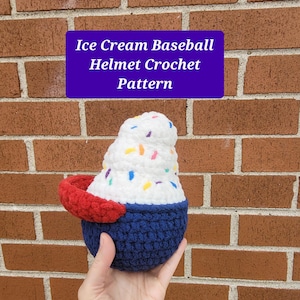May include: A crocheted ice cream cone baseball helmet pattern. The helmet is white with colorful sprinkles and a blue and red base.