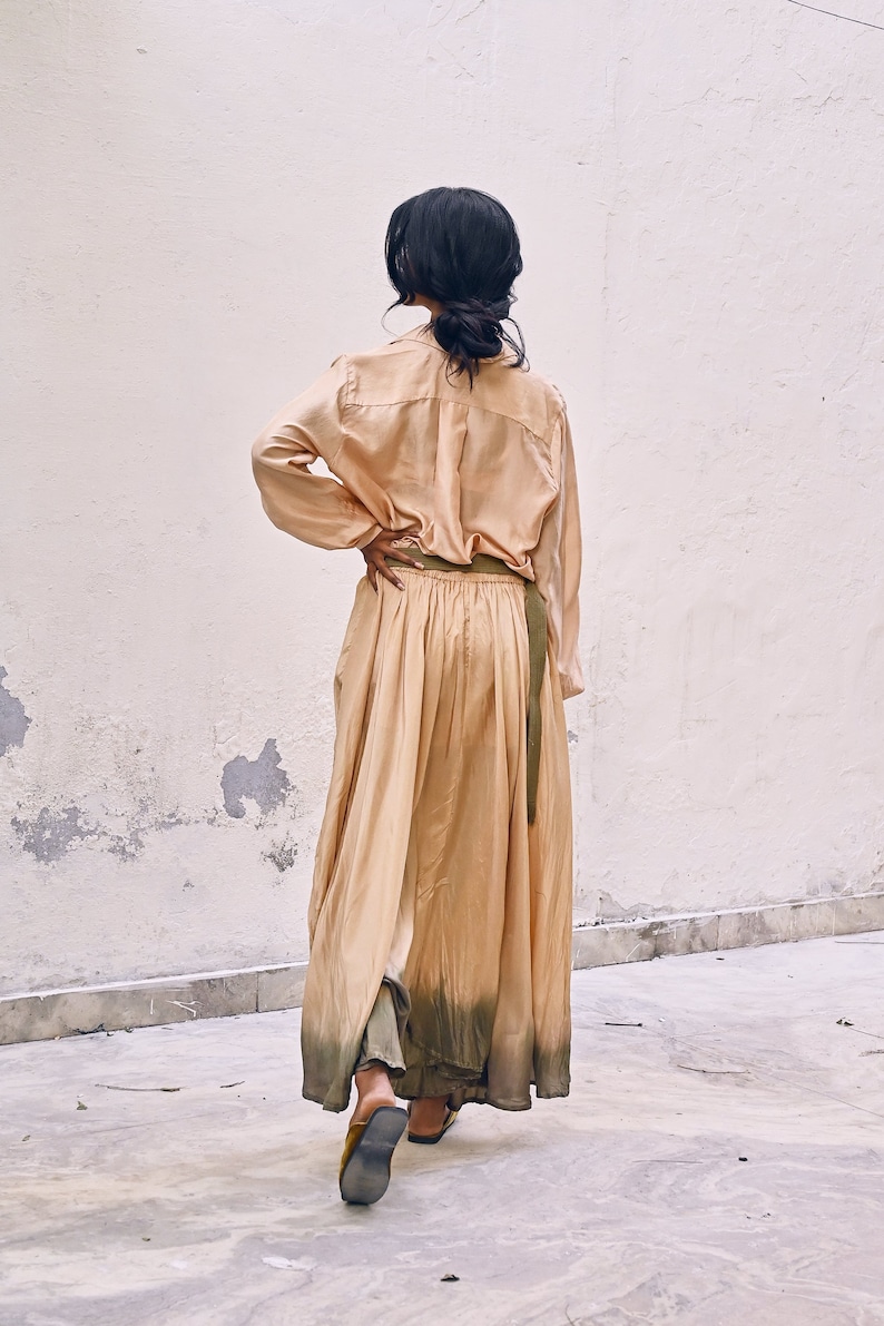 May include: A long, flowing, peach-colored dress with a green ombre effect at the hem. The dress has a long sleeve shirt bodice and a matching green belt.