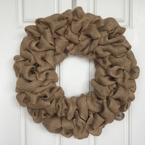 K&ouml;nnte beinhalten: Ein brauner Burlap-Kranz mit einer ger&uuml;schten Textur. Der Kranz ist aus Burlap-Band gefertigt und perfekt f&uuml;r einen rustikalen oder Landhausstil.