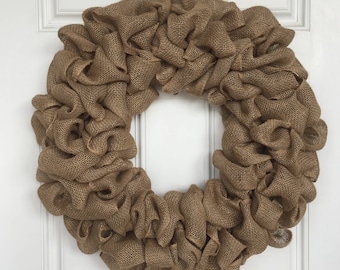 May include: A brown burlap wreath with a ruffled texture. The wreath is made of burlap ribbon and is perfect for a rustic or farmhouse decor style.
