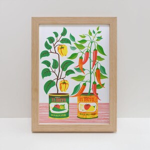 May include: A framed print of a colourful illustration of two potted plants. One plant has red and orange chilli peppers and the other has yellow bell peppers. Both plants are in front of cans of El Pato salsa. The can on the left says "Salsa de Jalapeño" and the can on the right says "Salsa de Chile Fresco".