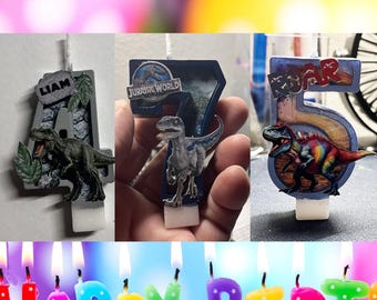 May include: Three custom birthday candles shaped as the numbers 4, 7, and 5. The number 4 features a T-Rex and the name LIAM. The number 7 displays a blue raptor and the Jurassic World logo. The number 5 shows a colorful dinosaur and the word ROAR.
