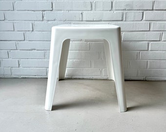 May include: A white plastic stool with a simple, modern design. The stool has a square top and four legs.