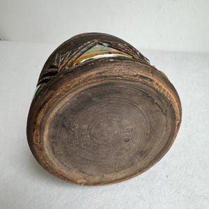 K&ouml;nnte beinhalten: Eine braune Keramikvase mit strukturierter Oberfl&auml;che und dunkler, erdiger Farbpalette. Die Vase weist geschnitzte Details und einen leicht ausgestellten Rand auf. Auf der Unterseite der Vase steht "Rimos Sweden" und die Nummer "649".