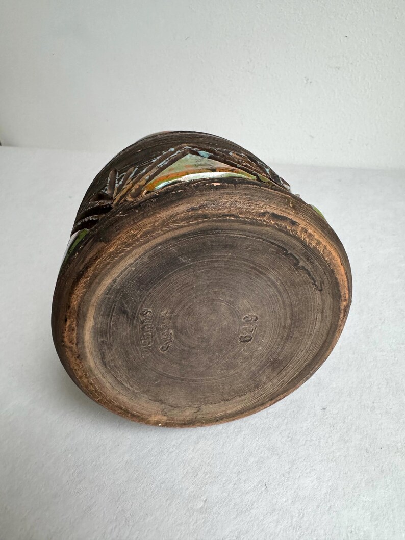K&ouml;nnte beinhalten: Eine braune Keramikvase mit strukturierter Oberfl&auml;che und dunkler, erdiger Farbpalette. Die Vase weist geschnitzte Details und einen leicht ausgestellten Rand auf. Auf der Unterseite der Vase steht "Rimos Sweden" und die Nummer "649".
