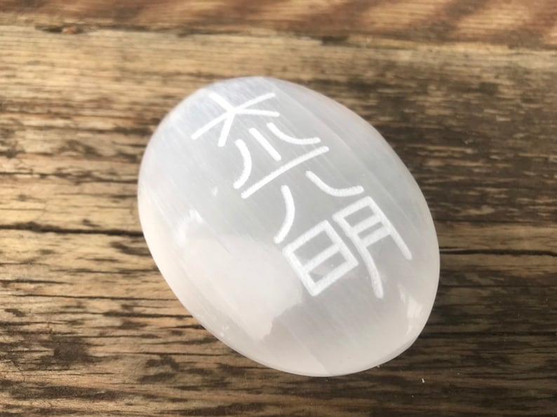 Pode incluir: Ovo de cristal de selenita branco com o s&iacute;mbolo chin&ecirc;s da "paz" gravado nele.