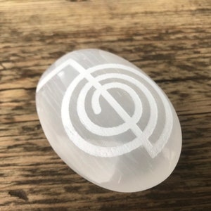 Pode incluir: Pedra de selenita branca em forma de palma com um s&iacute;mbolo de espiral branco talhado, tamb&eacute;m conhecido como labirinto ou s&iacute;mbolo de chakra.