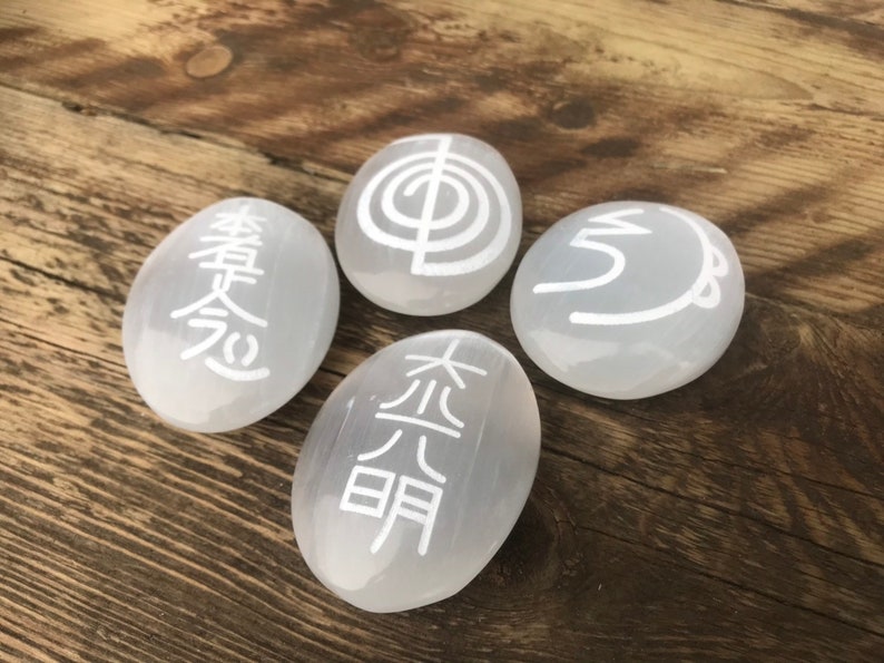 Pode incluir: Quatro pedras brancas de selenita com diferentes s&iacute;mbolos gravados nelas. Os s&iacute;mbolos s&atilde;o "Om", "Tai Chi", "Wu Xing" e "Hsing Shen".