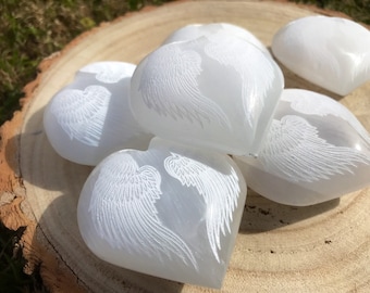 May include: A group of white selenite heart-shaped stones with etched angel wings.