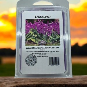 May include: A wax melt with a purple hyacinth flower image on the front. The back of the wax melt has a warning label, a QR code, and a barcode. The label reads "HYACINTH", "WWW.WALKERVILLECANDLES.COM", "WARNING", "USE ONLY IN WARMERS APPROVED FOR MELTING WAX. KEEP OUT OF REACH OF CHILDREN AND PETS. DO NOT EAT. DO NOT ADD WATER".