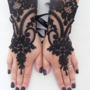 May include: A pair of black lace fingerless gloves with a floral design. The gloves have a ribbon tie at the wrist.