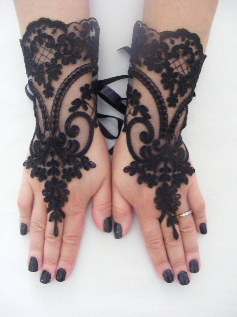 May include: A pair of black lace fingerless gloves with a floral design. The gloves have a ribbon tie at the wrist.