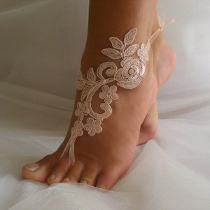 May include: A delicate ivory lace foot jewelry with floral designs. The lace is tied around the ankle and has a ribbon that ties around the toes.
