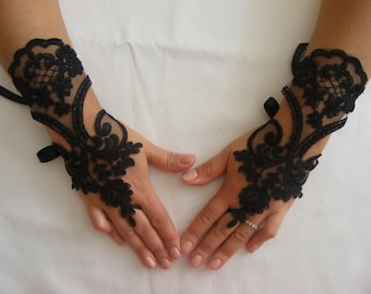 May include: A pair of black lace fingerless gloves with a floral design. The gloves have a black ribbon tie at the wrist.