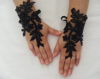 May include: A pair of black lace fingerless gloves with floral designs and sequins. The gloves are tied at the wrist with a black ribbon.
