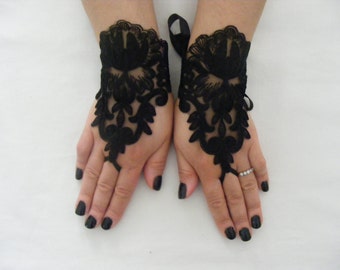 May include: A pair of black lace fingerless gloves with a floral design. The gloves have a ribbon tie at the wrist.
