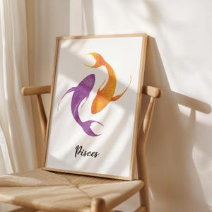 May include: Framed art print featuring two stylized fish in purple and orange glitter, representing the Pisces zodiac sign. The word "Pisces" is written in a cursive font below the fish. The artwork is displayed on a wooden chair.