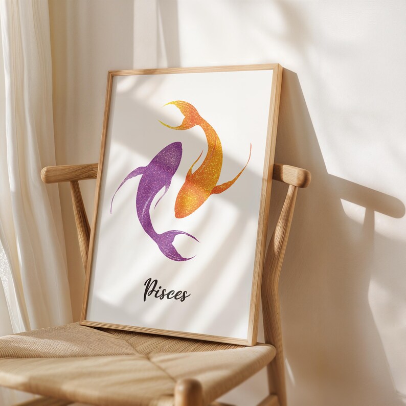 May include: Framed art print featuring two stylized fish in purple and orange glitter, representing the Pisces zodiac sign. The word "Pisces" is written in a cursive font below the fish. The artwork is displayed on a wooden chair.