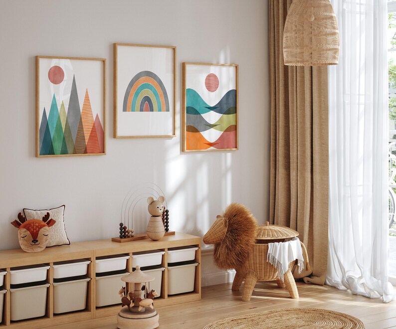 May include: Three abstract geometric wall art prints featuring a rainbow, mountains, and waves. The prints are framed in natural wood and have a white background. The prints are hanging on a white wall above a wooden shelf with storage bins.
