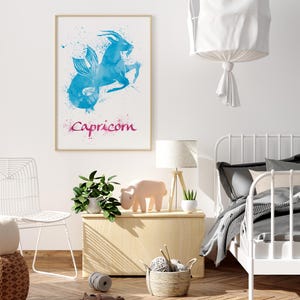 May include: A framed watercolor print featuring the Capricorn zodiac sign in shades of blue and pink. The artwork depicts a goat-fish hybrid with the word "Capricorn" below. The print hangs above a wooden chest with a lamp and decorative items.